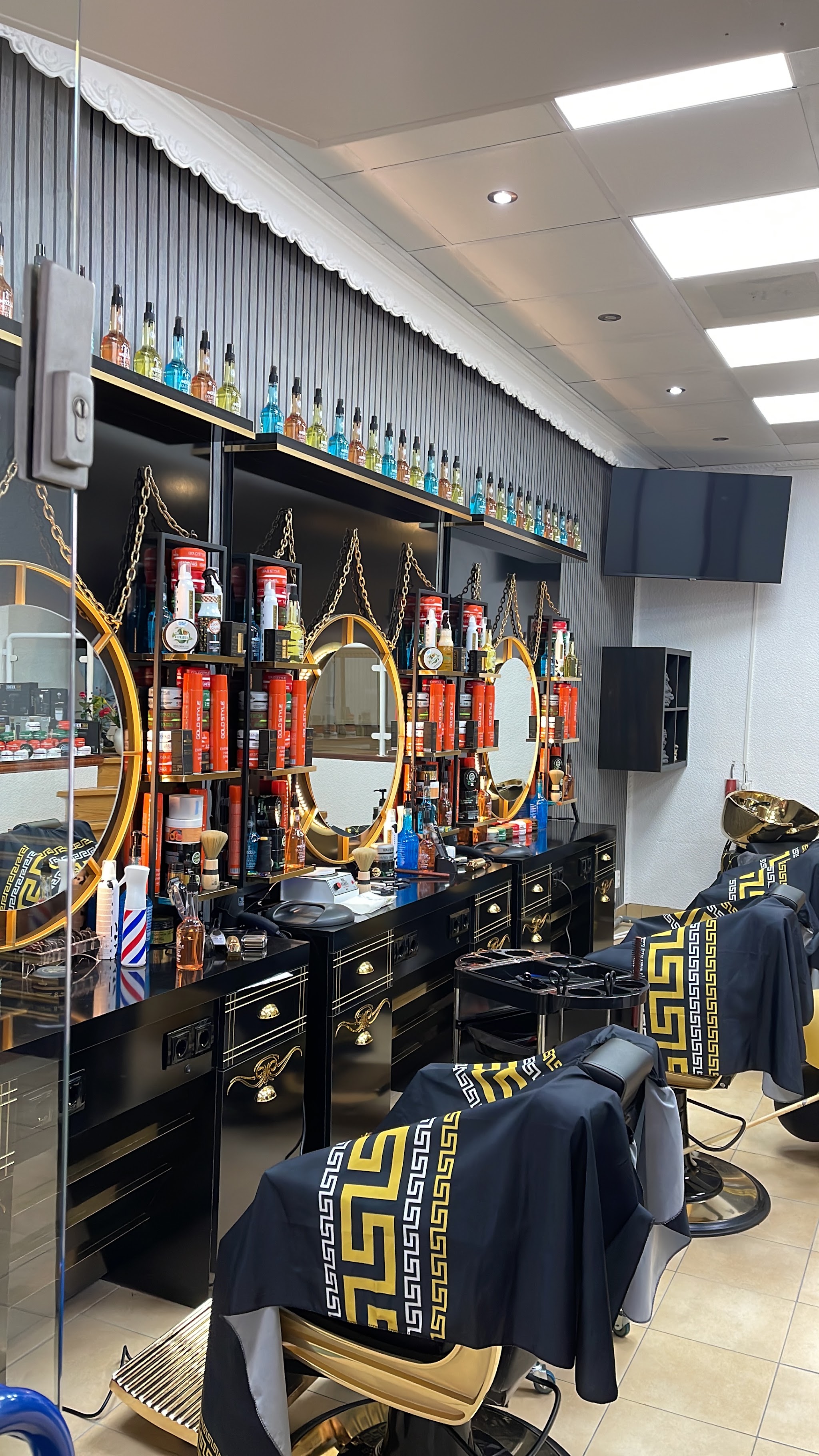 De kappersstoelen, ronde gouden spiegels en producten in Kapsalon Manee