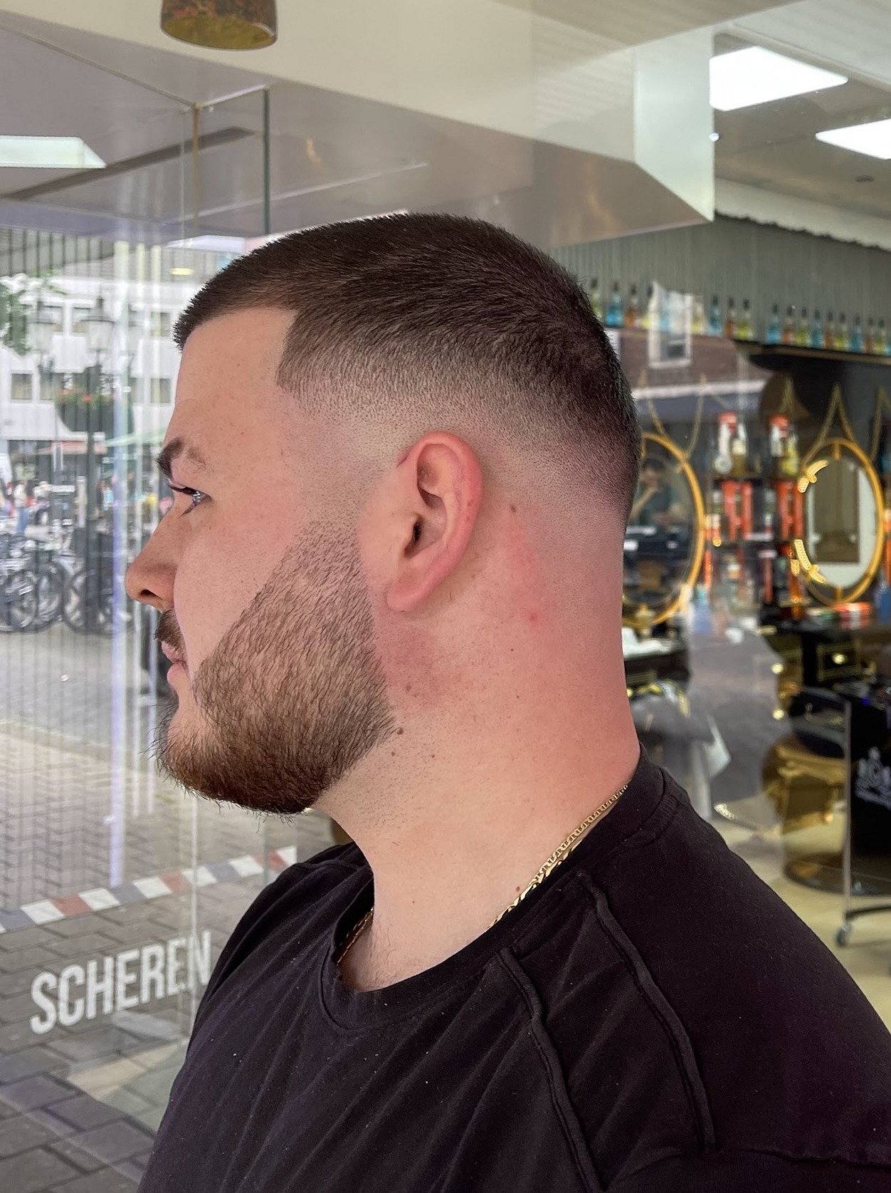 Afgewerkt kort kapsel met overloop en verzorgde baard, van opzij gezien